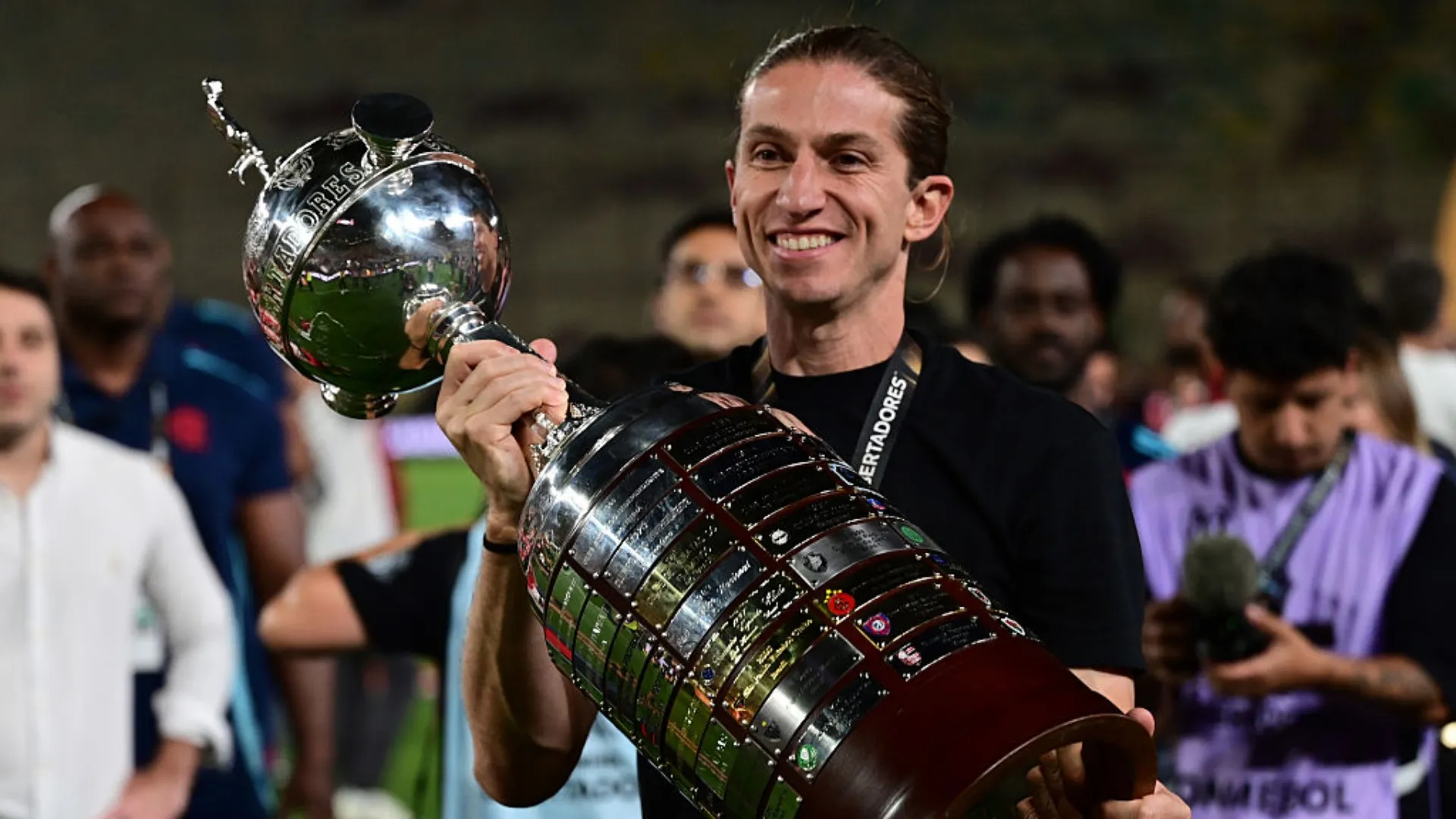 Filipe Luís segurando a taça da Copa Libertadores, enquanto sorri